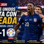Jugadores de Estados Unidos celebran una contundente victoria por 4-1 sobre Paraguay en el Mundial 2026. Folarin Balogun lidera la celebración tras marcar un doblete histórico, mientras el marcador destaca el triunfo de EE. UU. en su debut mundialista ante una multitud en un estadio lleno.